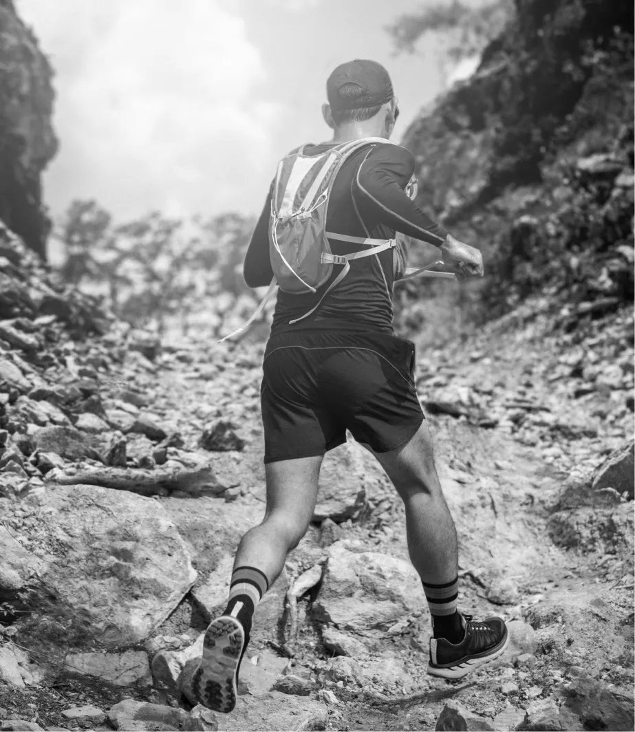 Ein Sportler beim Geländelauf. Schwarz-weiß-Bild, von hinten fotografiert.